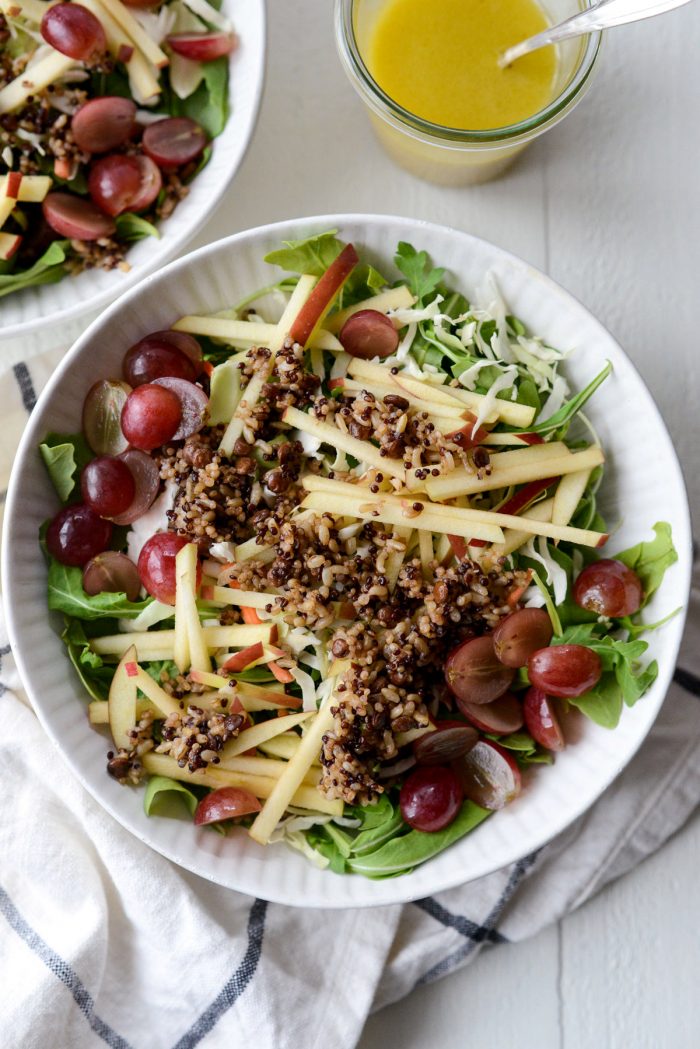 arugula, slaw, apple, grape and cereal in bowl.