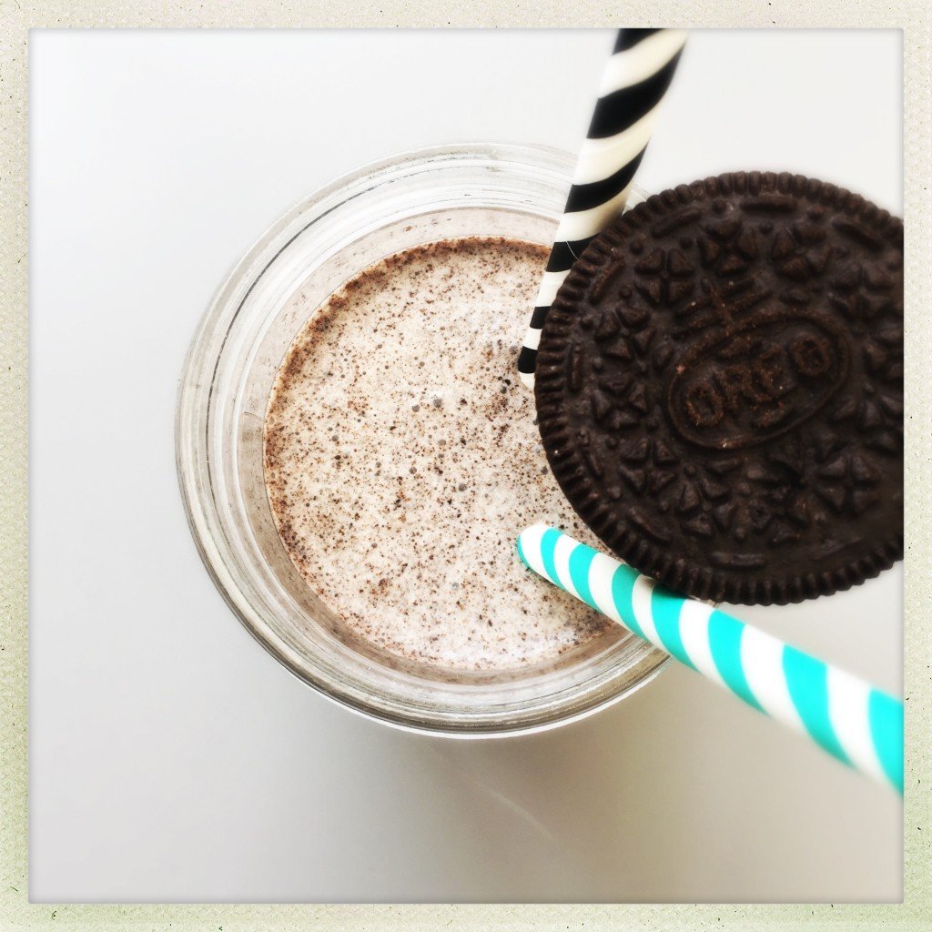 cup with homemade oreo milkshakes served with two striped paper straws and Oreo cookies