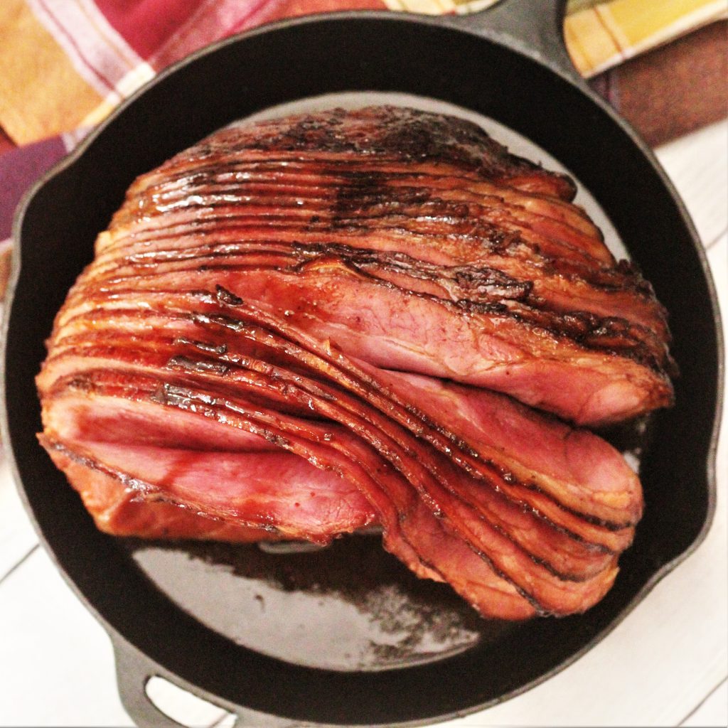Top view of a spirally sliced ​​twice-smoked ham in a cast iron skillet.