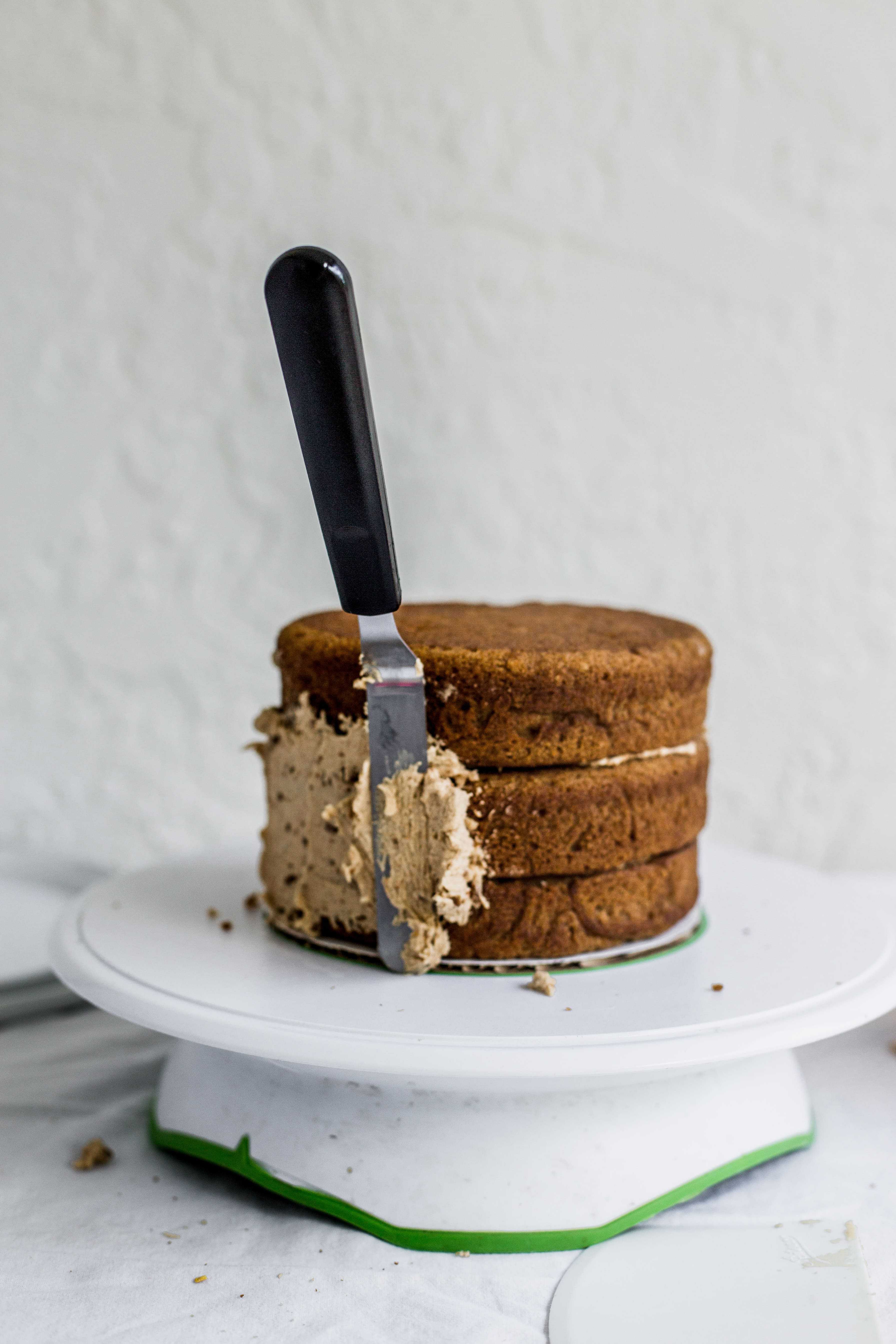 An offset spatula lifting up a cake on a white turntable