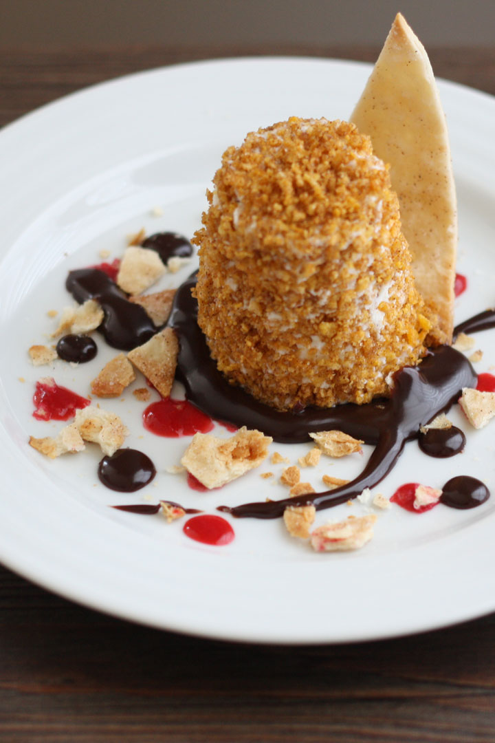 Serve Mexican fried ice cream on a plate with chocolate sauce, raspberry sauce, and cinnamon tortillas.