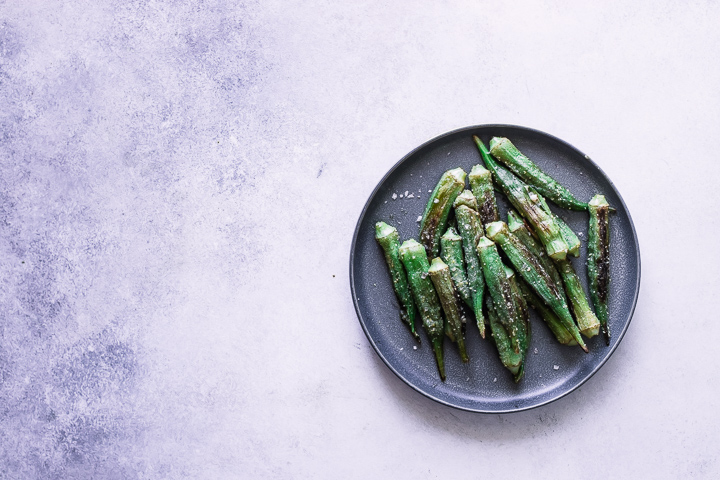 Okra on plate on white and blue table.