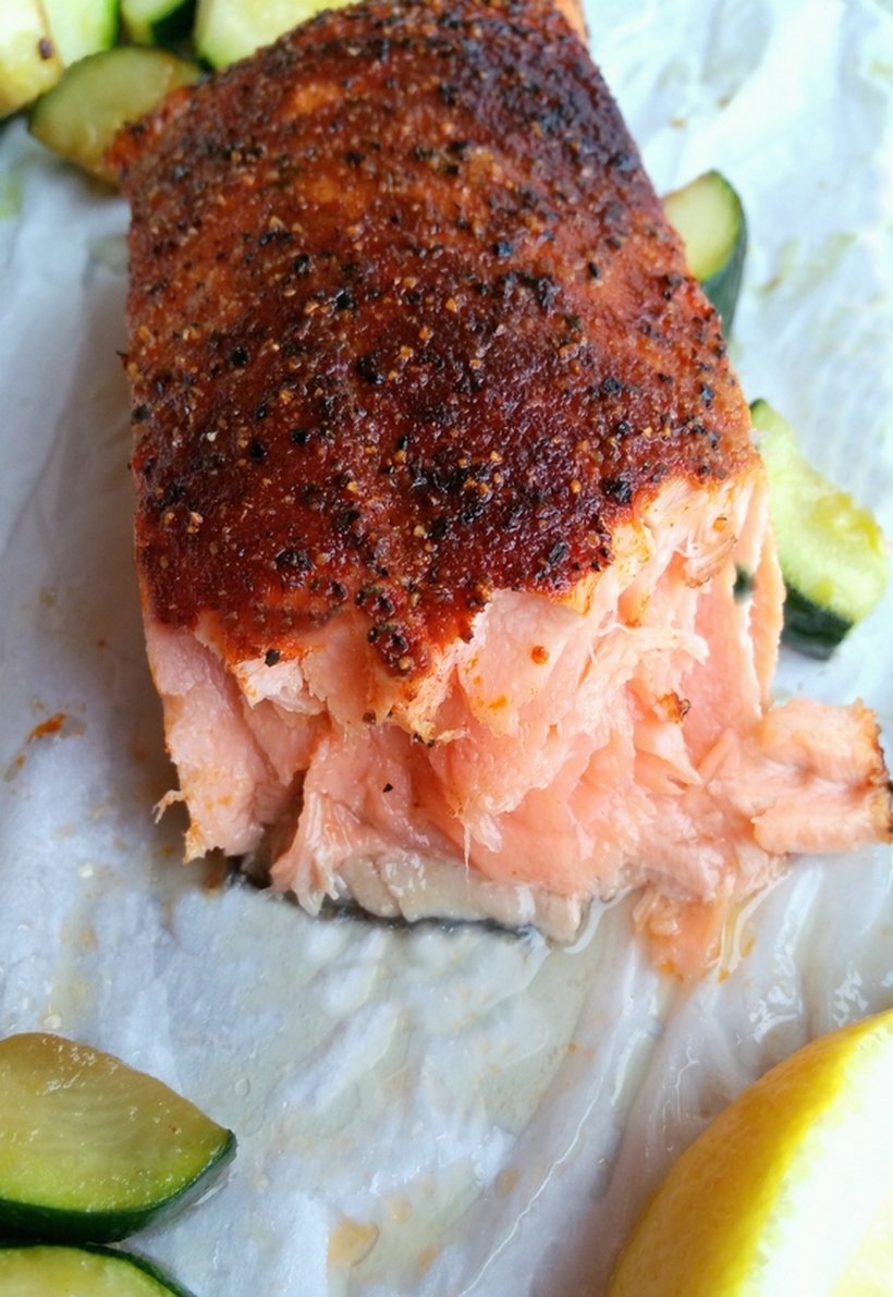 A piece of cooked salmon is peeled off to reveal the flesh inside.