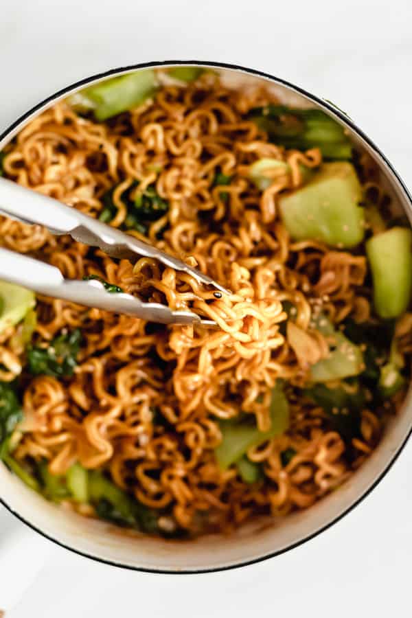 two bowls of ramen noodles with scallions and sesame seeds