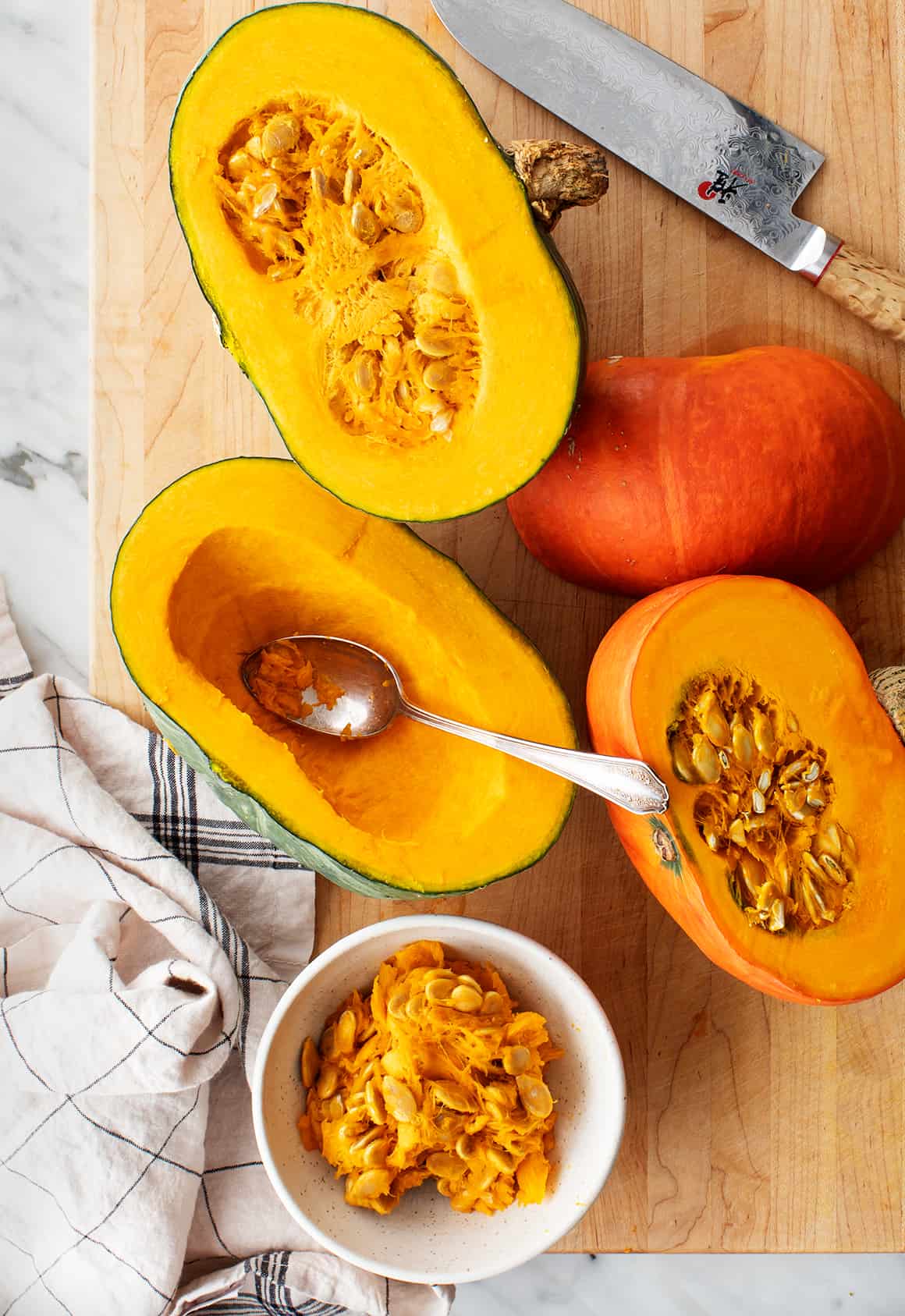 Japanese pumpkin cut in half on a cutting board with some seeds grated