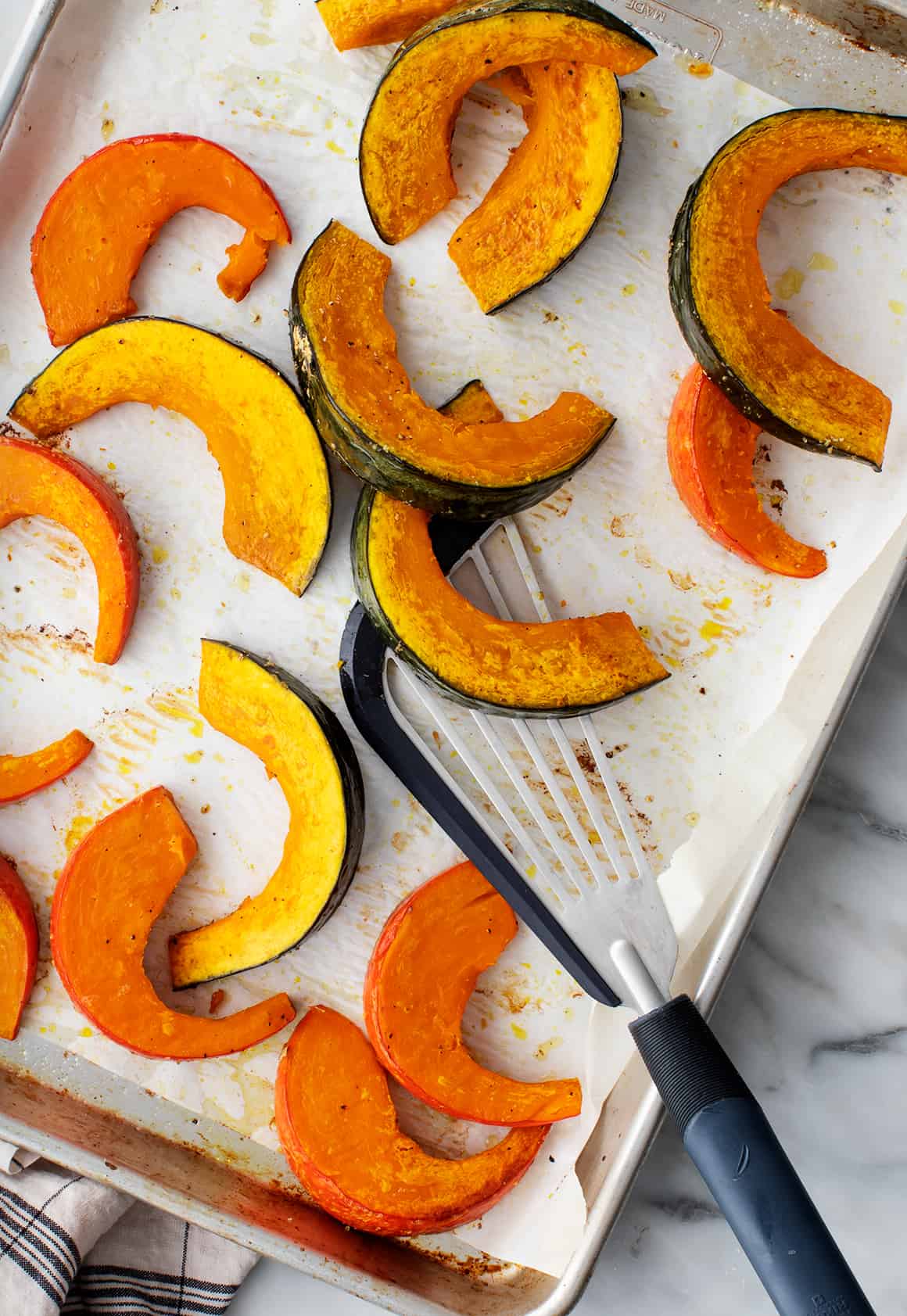 Grilled kabocha squash on a baking tray with a spoon