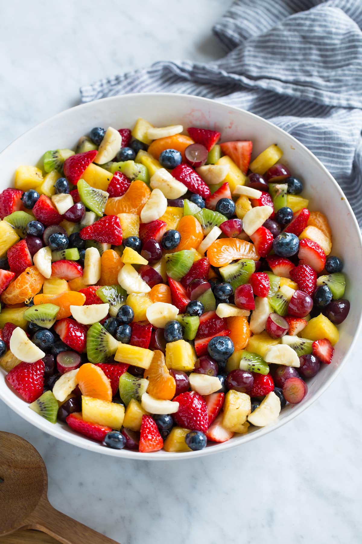 Fruit salad with chopped fresh fruit in a large salad bowl set on a marble top.