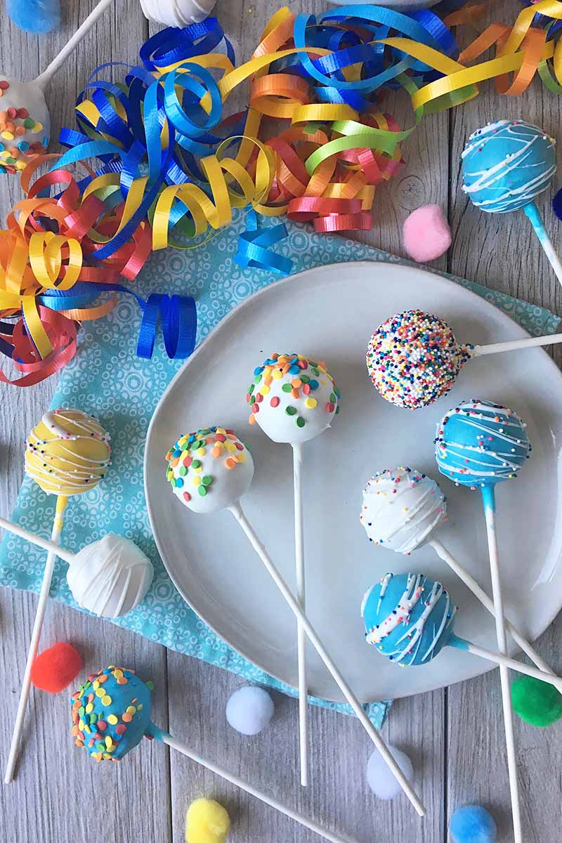 Vertical top-down image of assorted treats on sticks surrounded by streamers.