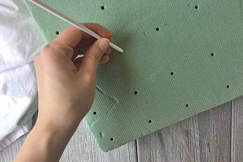 Horizontal image of a hand prepping a foam board.