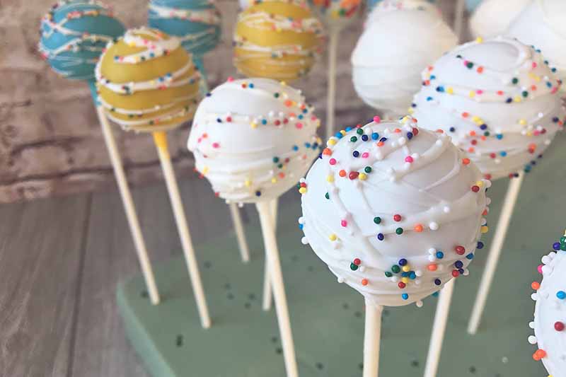 Horizontal image of drying cake pops on a foam board.