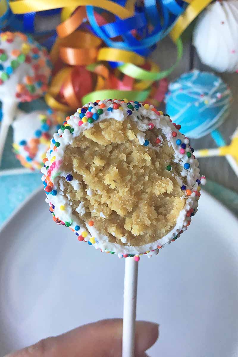 Vertical image of a cake pop with a bite taken out of it.