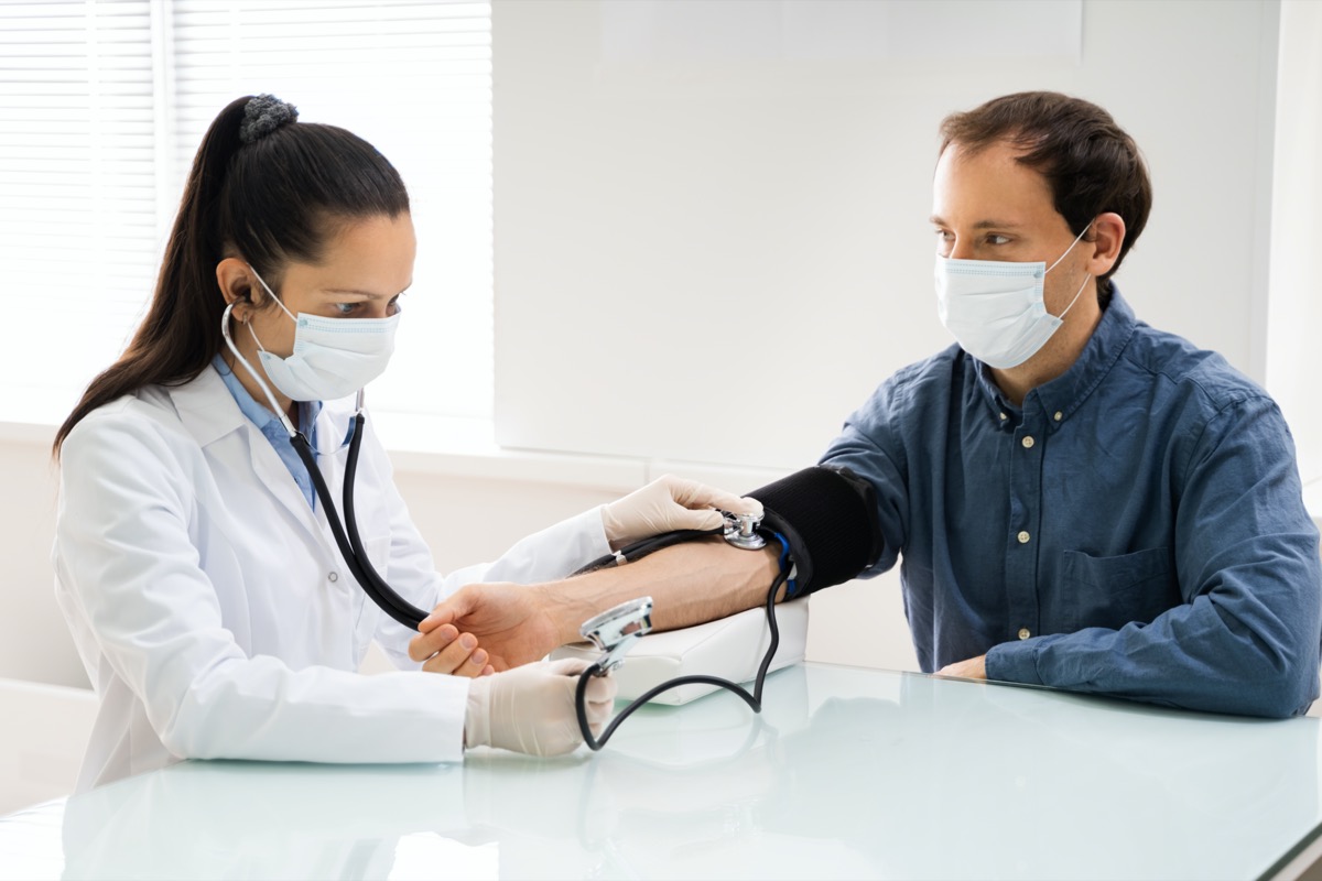 Doctor checking high blood pressure in a mask