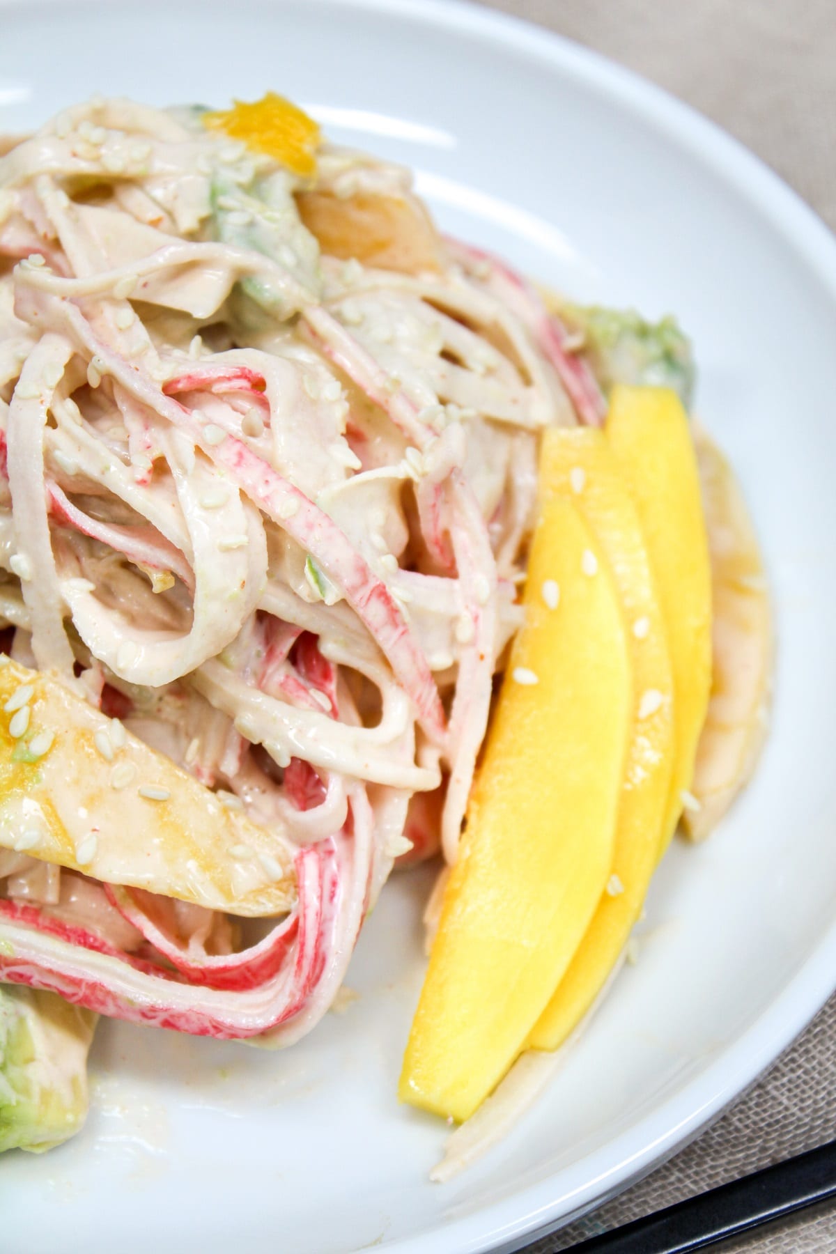 spicy kani salad on plate with sliced ​​mango