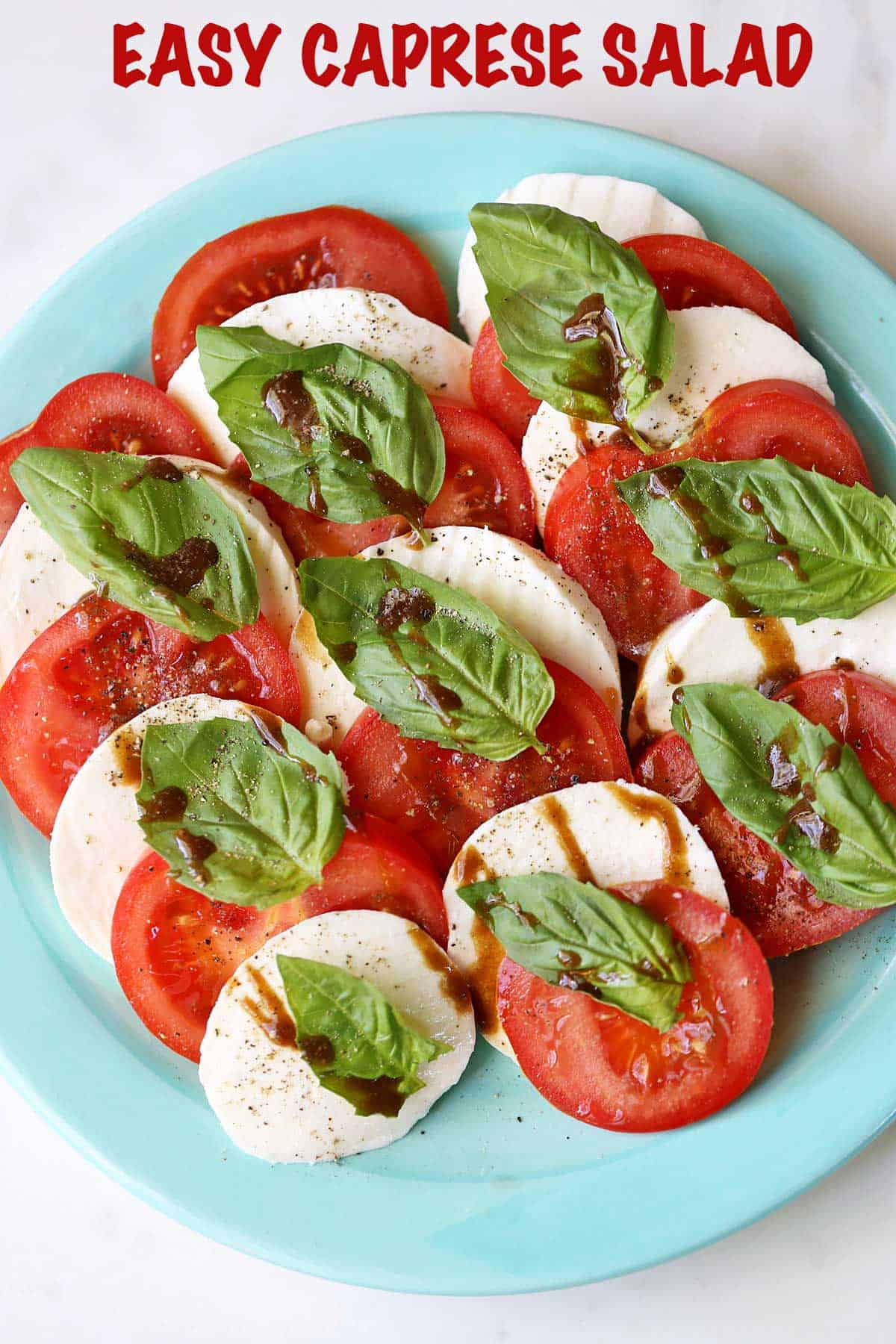 Caprese salad with tomato slices and mozzarella cheese is served on a green plate.