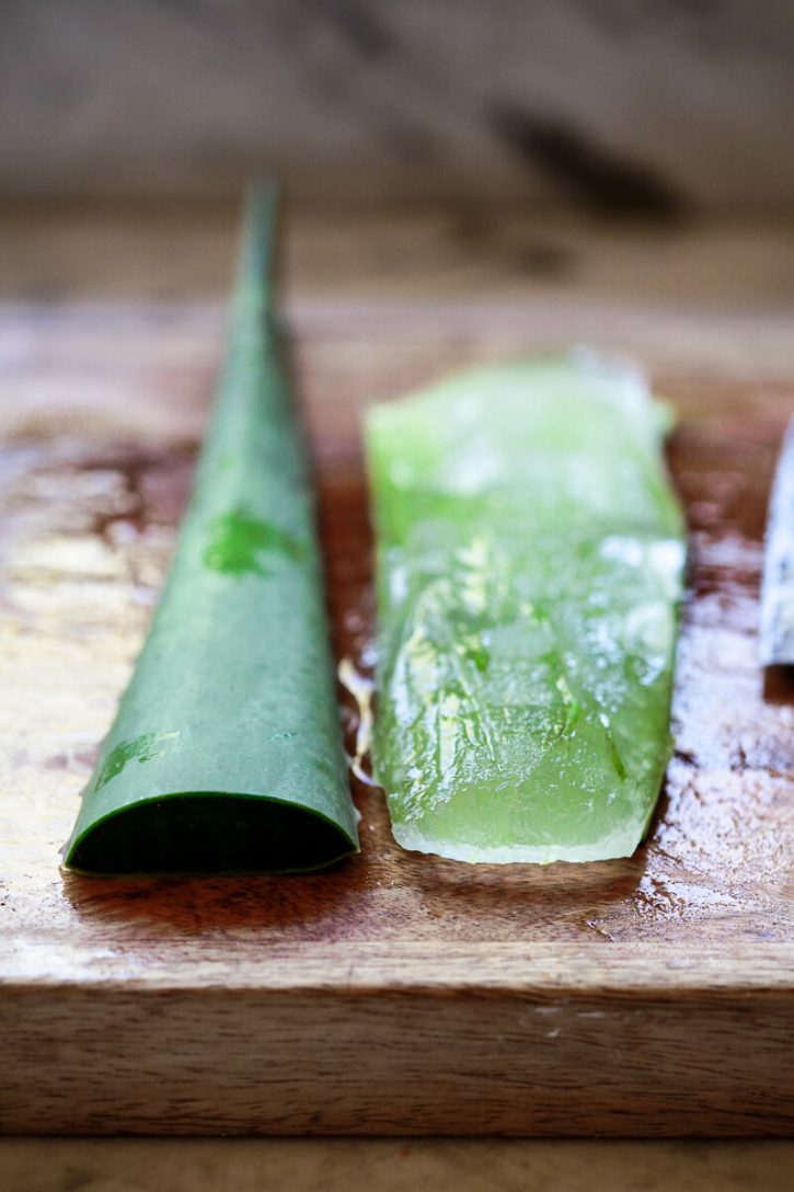 An aloe leaf is peeled to reveal the aloe vera gel inside.