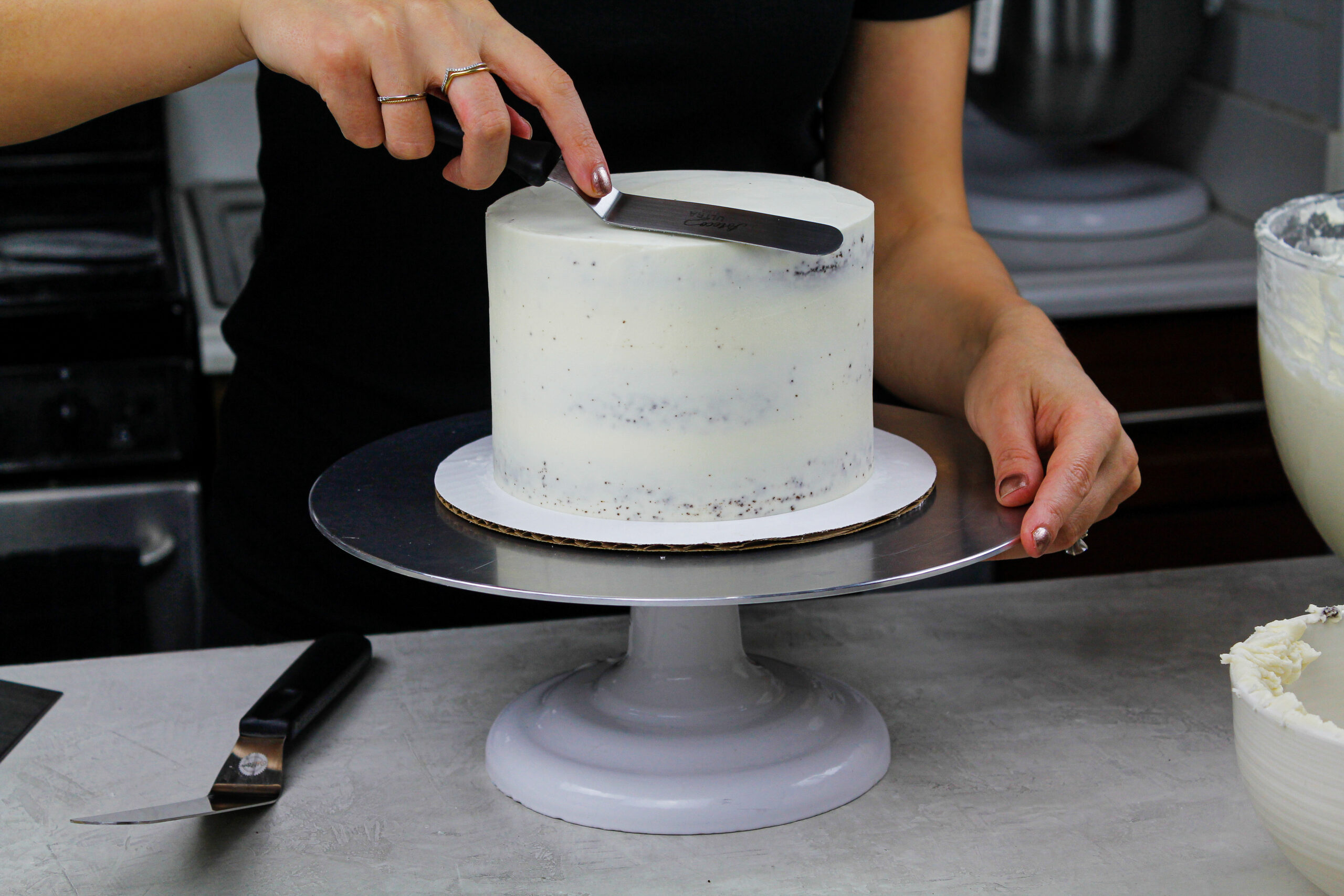 image of a buttercream cake being frosted with sharp edges and smooth sides to show How to Frost a Cake Smoothly