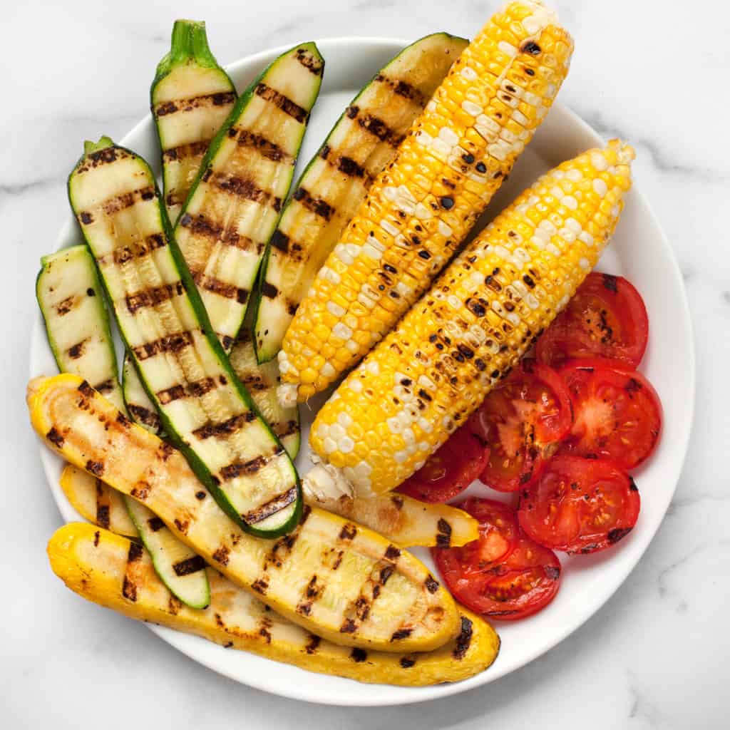 Place zucchini, squash, corn and grilled tomatoes on a plate