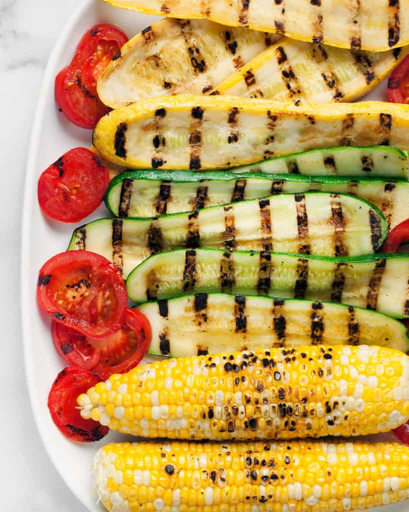 Place zucchini, squash, corn and grilled tomatoes on a plate
