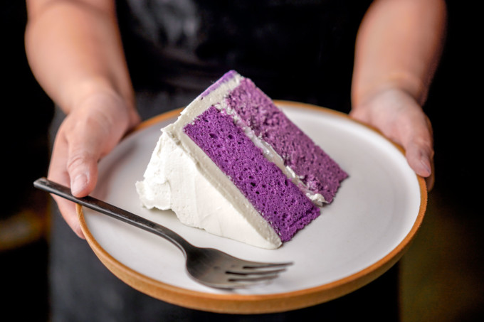 holding a slice of ube cake on a plate