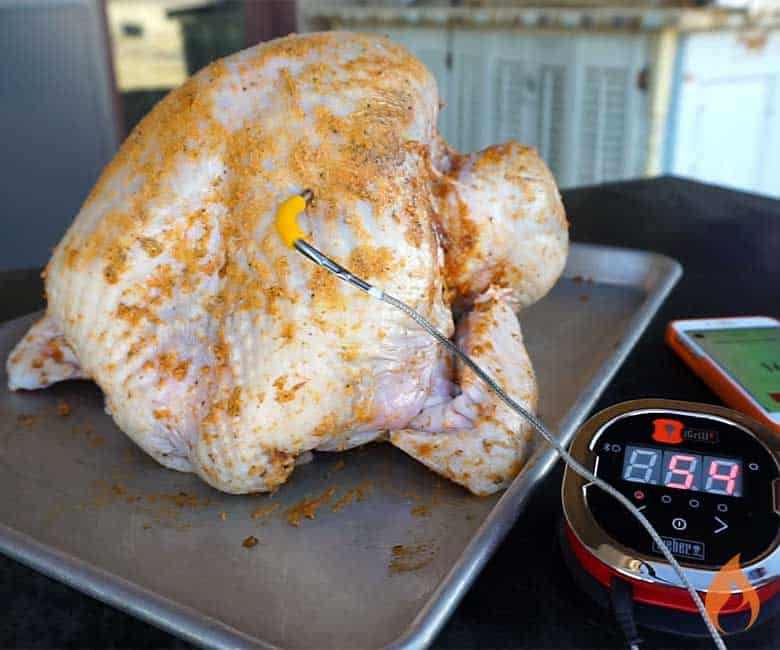 raw turkey with rub on a pan with temperature probe attached