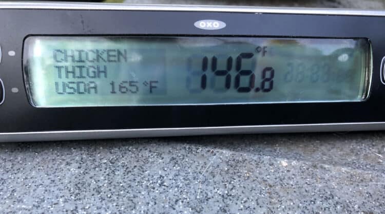 Meat thermometer shows progress on the optimal temperature for chicken legs on the grill