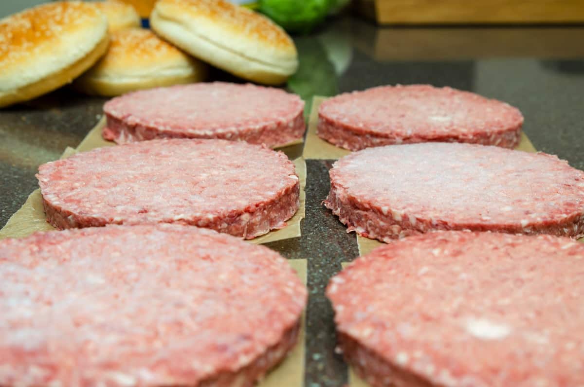 defrost six frozen burgers sitting on parchment squares, on the kitchen counter