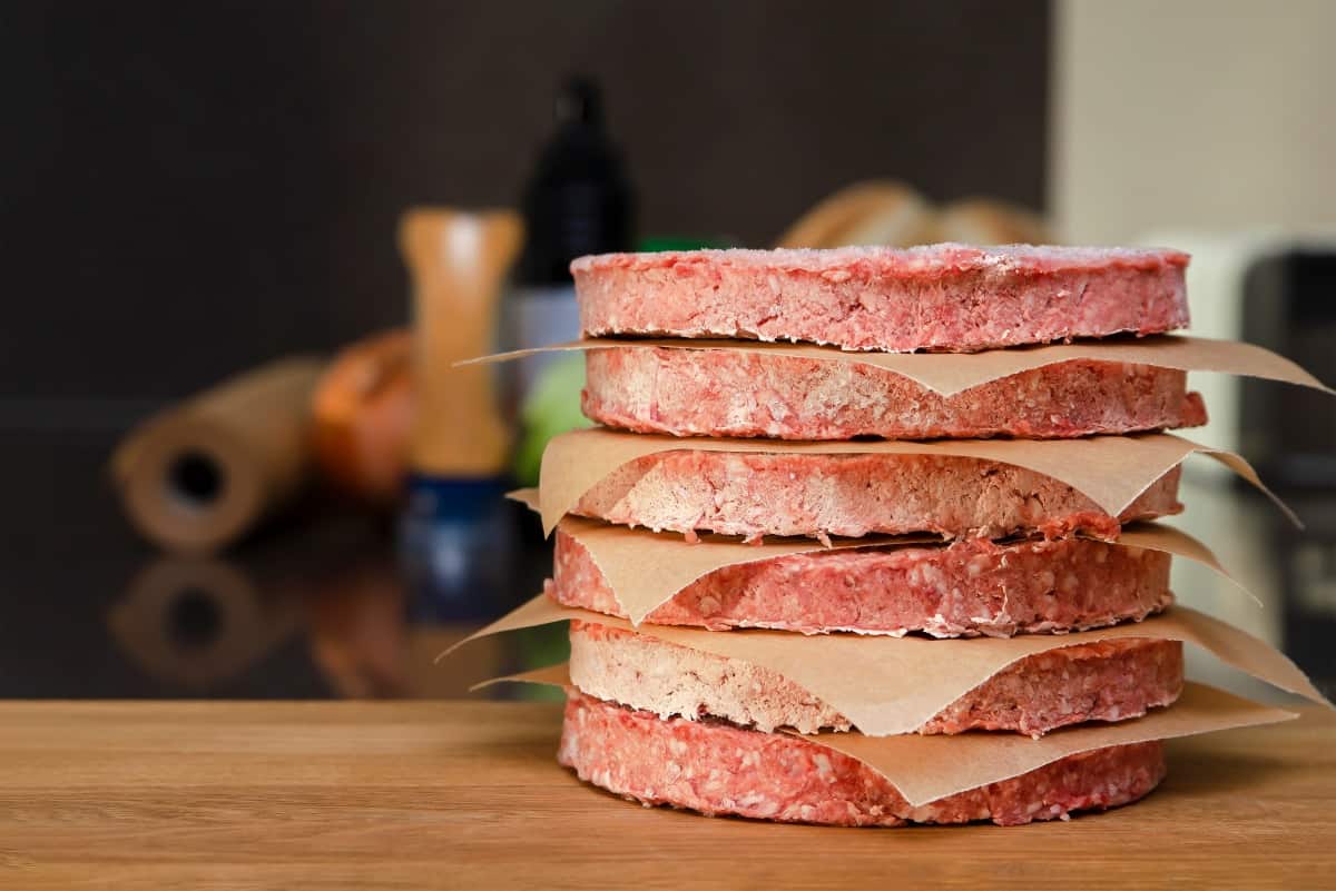 A stack of frozen burgers separated by parchment squares