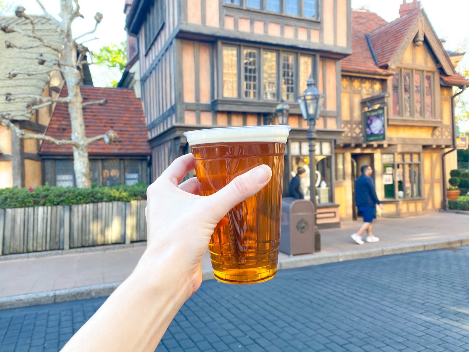 womans hand holding a brown beer with UK buildings in the background on an epcot drink around the world trip