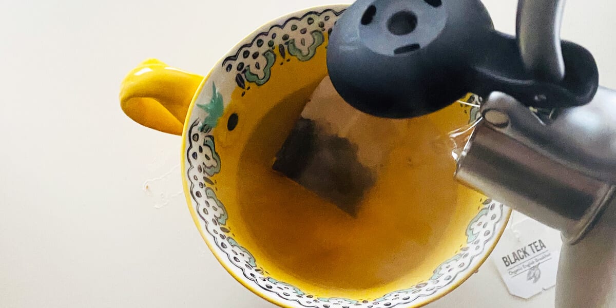 Pour hot water from the teapot into the teacup