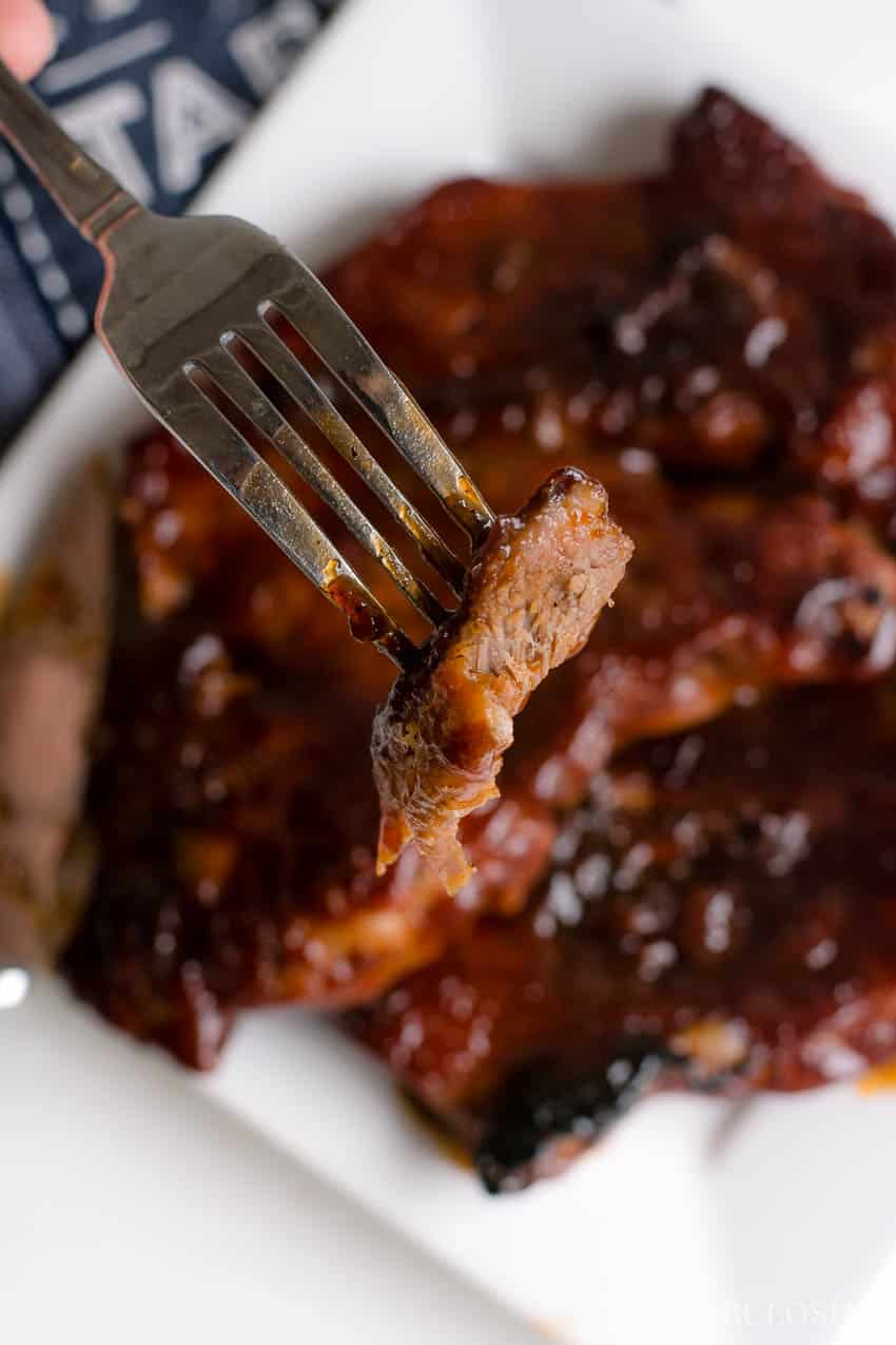 A piece of pork on a fork, ready to bite