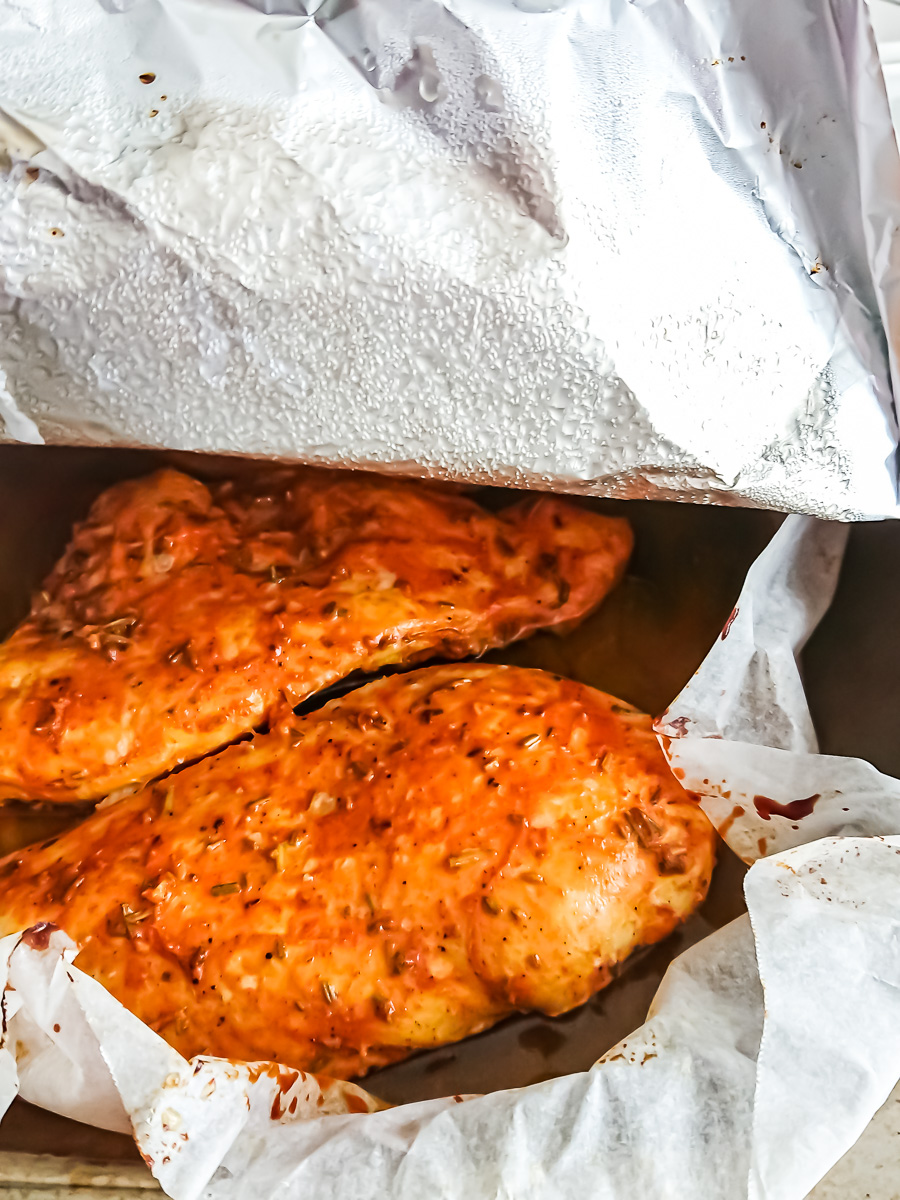 Oven-roasted chicken breasts in a baking tray, covered with aluminum foil