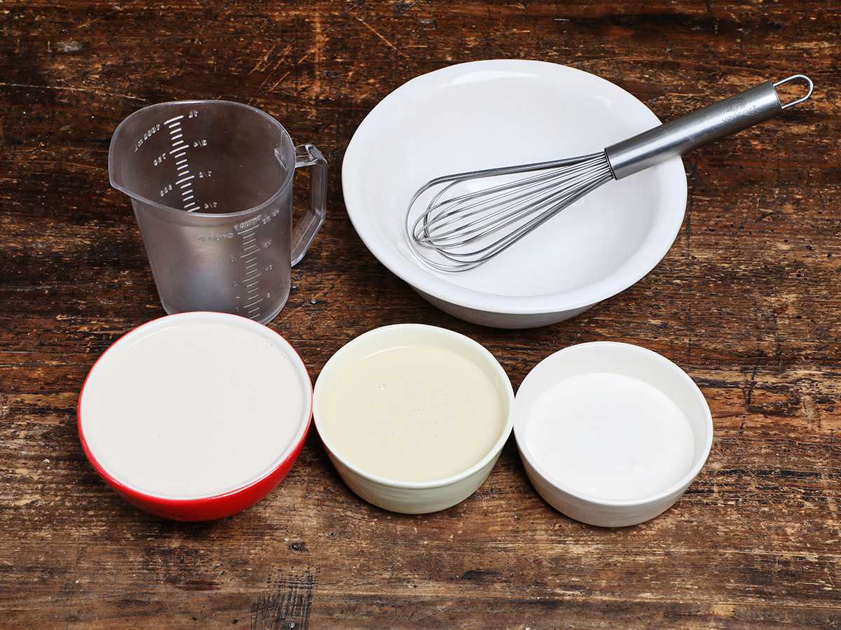 Three milks in bowls with measuring cup and wire whisk
