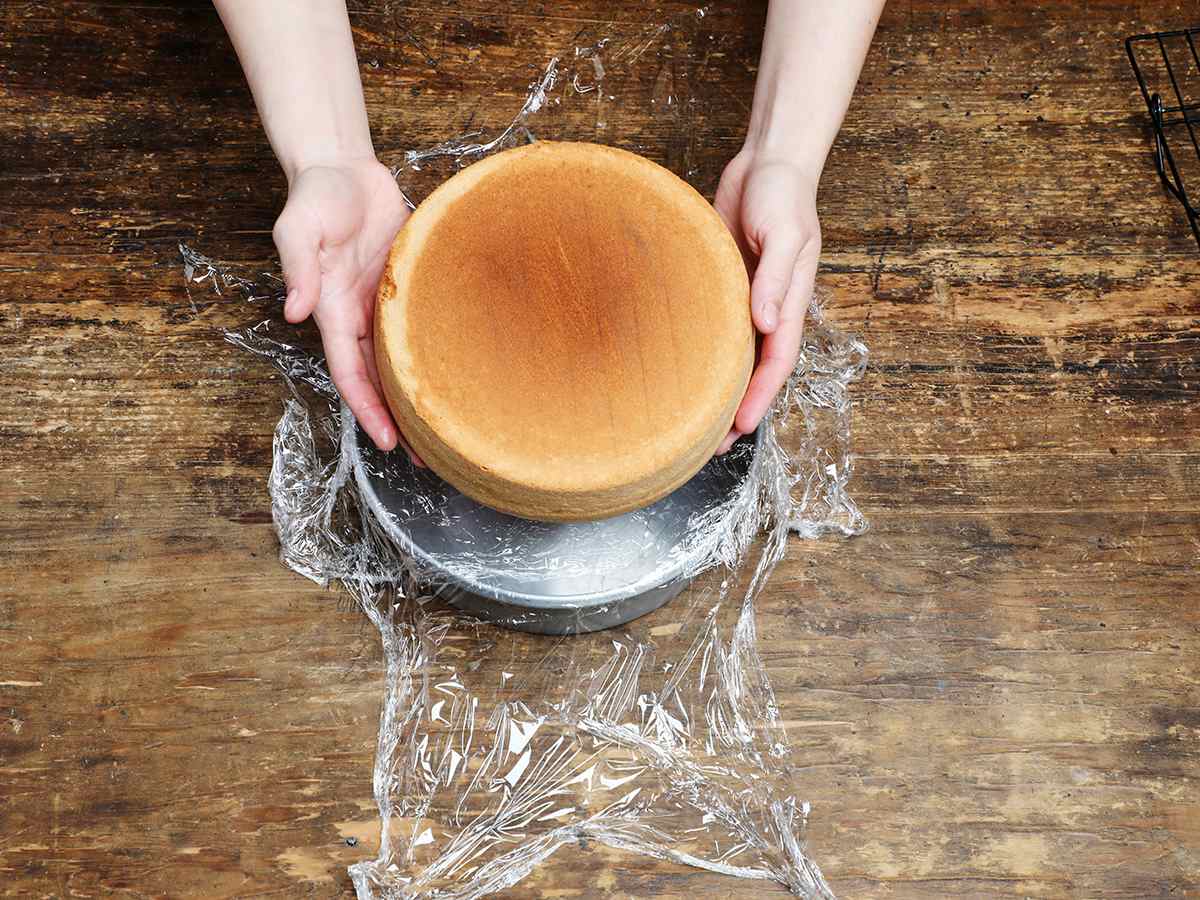 Placing cake into pan lined with plastic wrap