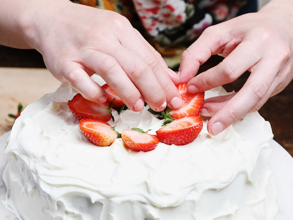 Decorating tres leches cake with strawberries