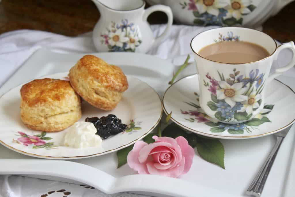 Afternoon tea cupcakes with a cup of tea and a rose on a tray