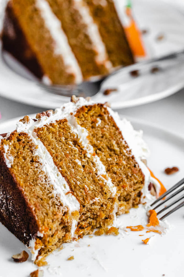 close up of half eaten carrot cake on a white plate