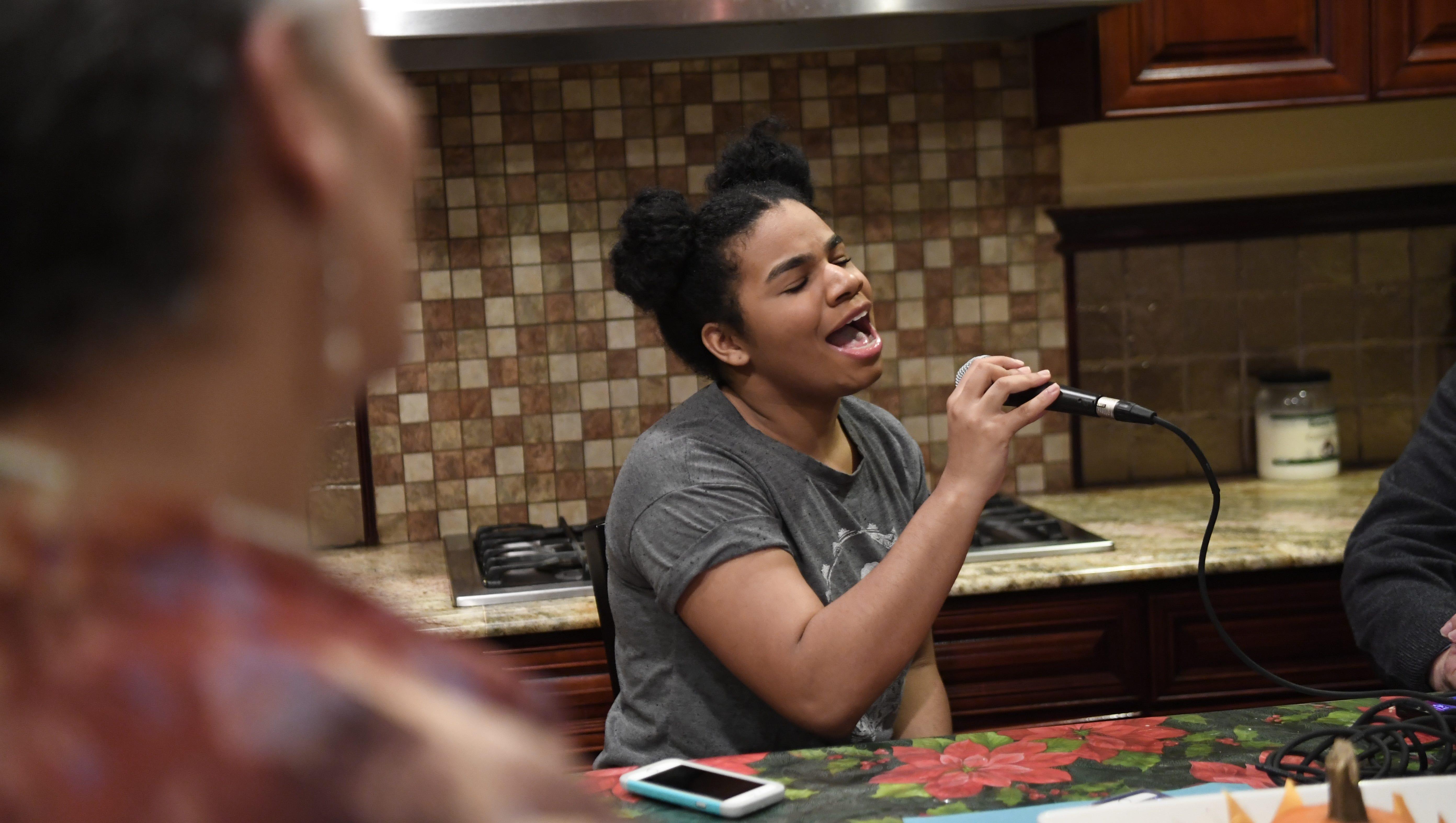 Jaqueline McDonald, left, listens to her daughter Wé as she sings in the kitchen of their home in Paterson.