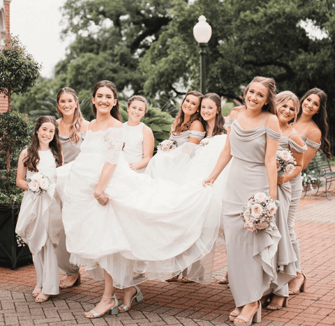 The bridal party follows the bride and brings her dress