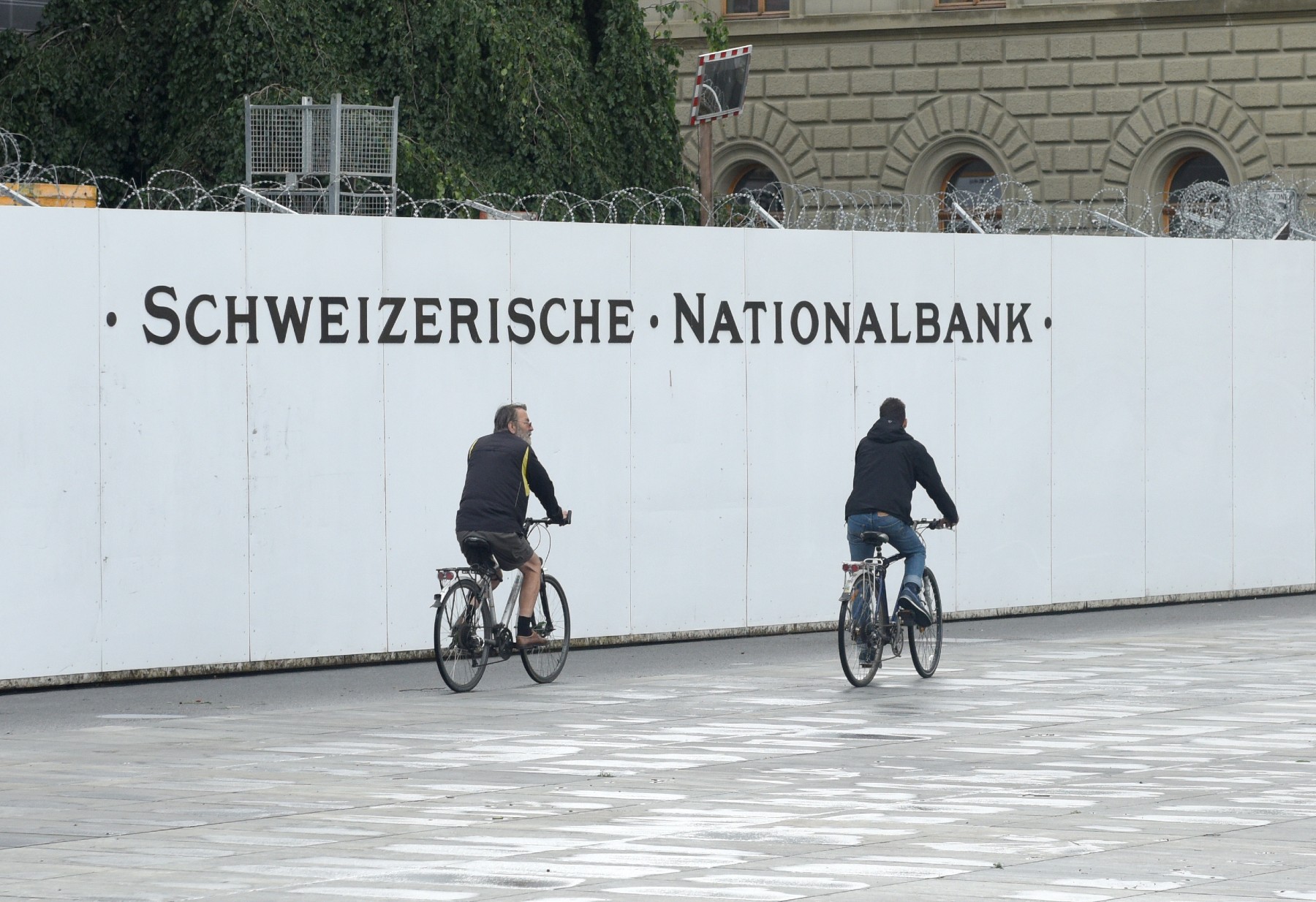 cyclists ride with a sign of the Swiss National Bank, why is Switzerland so rich