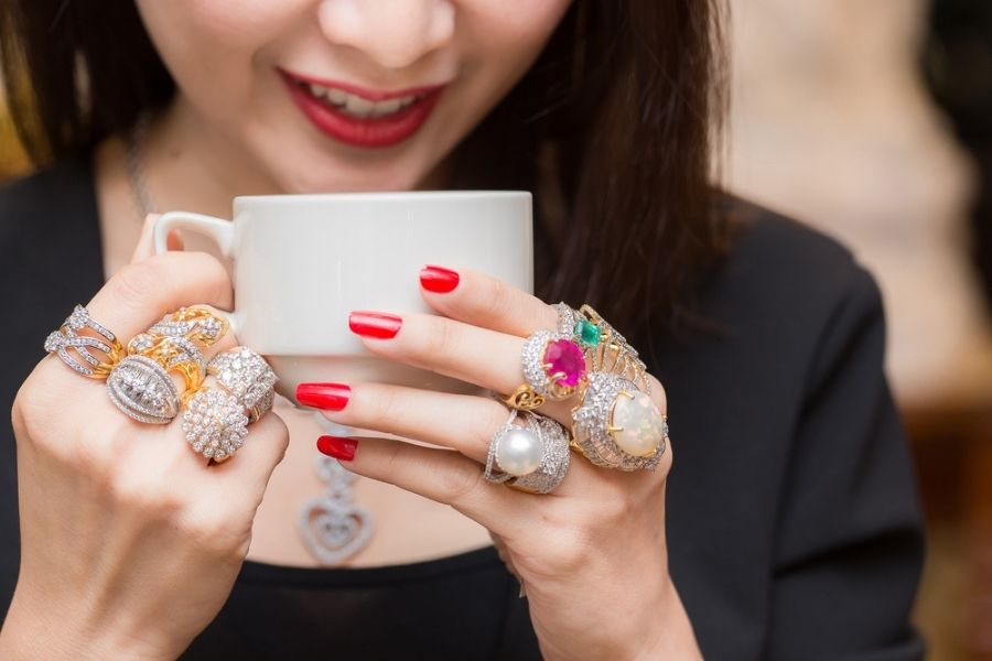 how many rings should you wear - woman with way too many rings drinking coffee