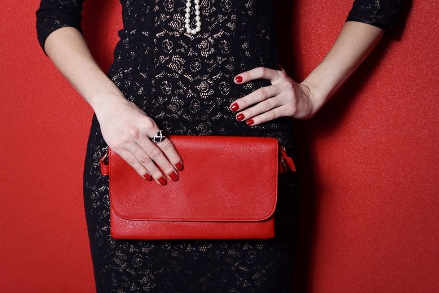woman in black dress with red purse matching her rings to her accessories