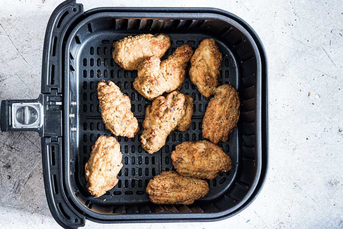 Horizontal image of chicken wings being reheated in an air fryer