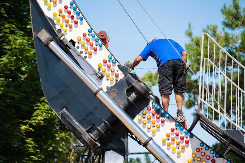 Maintenance worker with a hammer attempting to fix a roller coaster ride