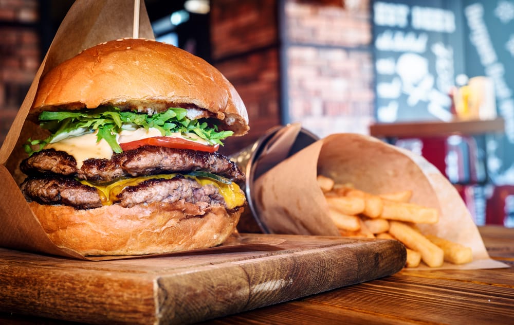 Fresh tasty burger and french fries on wooden table