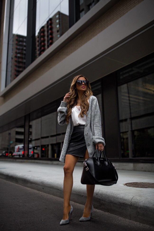 fashion blogger mia mia mine wears a gray cardigan from the spin and a faux leather skirt