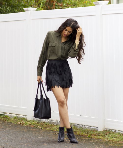 Green front pocket button up shirt with small black tassel skirt and boots