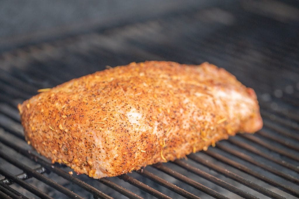 whole seasoned pork loin grilled on the grill of an oven.