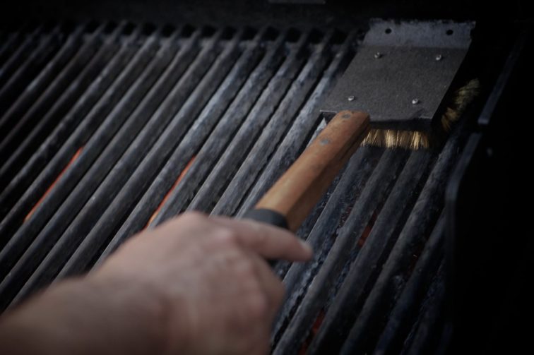 One person cleans the grill