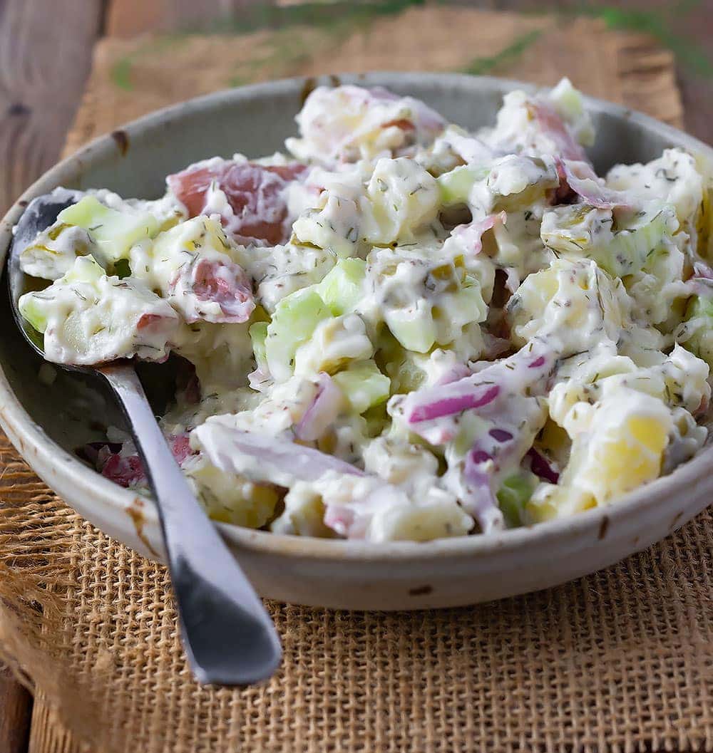 Vegan dill potato salad, red potatoes, celery, red onion, celery seeds, dill in beige bowl