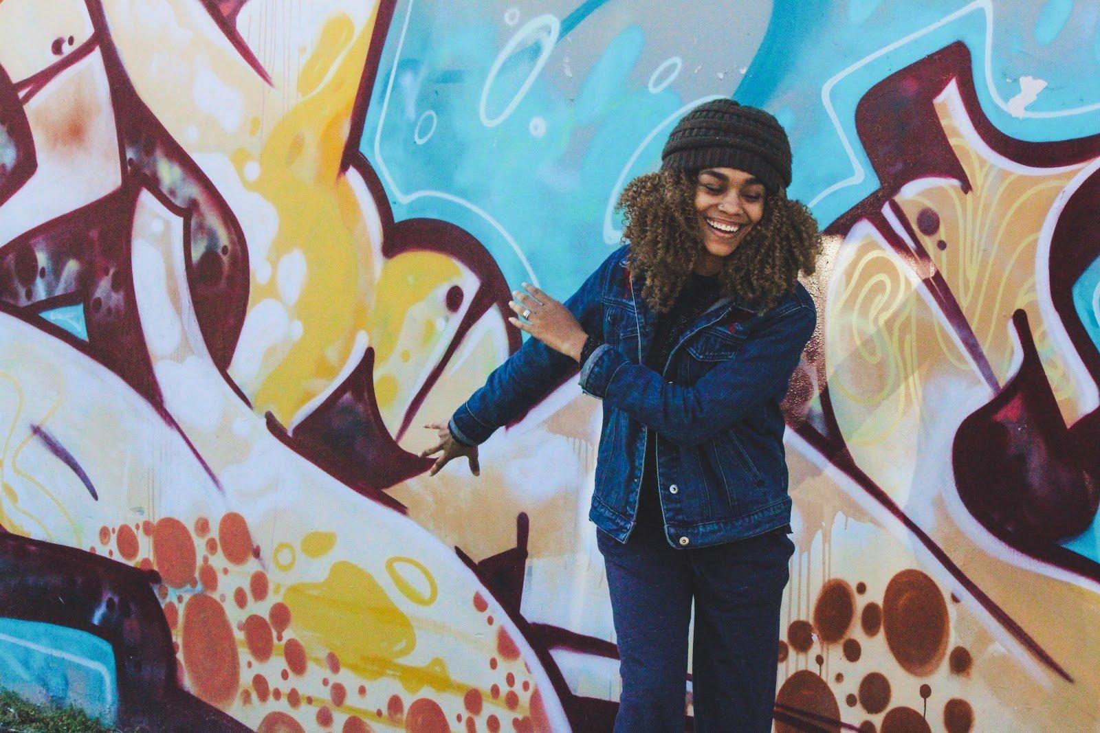 Rotten intestines: A happy woman in front of a colorful graffiti wall